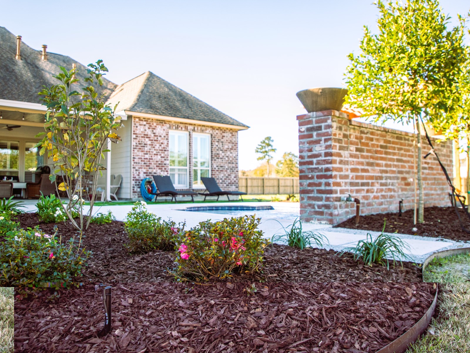 A completed courtyard landscape with beds, stone, and brick features